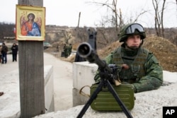 FILE - A separatist rebel guards a check point at the village of Luhanska, Ukraine, March 7, 2017.