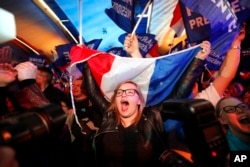 Supporters of far-right candidate Marine Le Pen, celebrate in Henin-Beaumont, northern France, after exit poll results of the first round of the presidential election are announced, April 23, 2017.