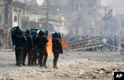 FILE: Cambodian riot police prepare to confront with garment workers throwing stones and bricks near a factory on the Stung Meanchey complex on the outskirts of Phnom Penh, Cambodia, Friday, Jan. 3, 2014.