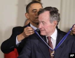 President Barack Obama awards former President George H.W. Bush the 2010 Medal of Freedom during a ceremony in the East Room of the White House in Washington, Tuesday, Feb. 15, 2011.