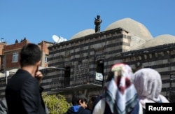 A member of police special forces stands guard on top of a building in Sur district before the arrival of Turkish Prime Minister Ahmet Davutoglu in the Kurdish-dominated southeastern city of Diyarbakir, Turkey April 1, 2016.