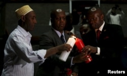 Kenya's National Counter Terrorism Center Director Martin Kimani, center, is assisted in lighting a candle during prayers to commemorate the first anniversary of the terrorist attack at the Garissa University College, in Kenya's capital, Nairobi, April 2, 2016.