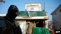 Afghan policeman stands guard next to damaged entrance of recently attacked Lebanese restaurant, Kabul, Jan. 18, 2014.