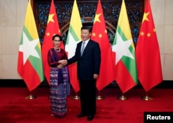Myanmar State Counselor Aung San Suu Kyi, left, and Chinese Premier Xi Jinping greet the media before a meeting in Beijing, Aug. 19, 2016.