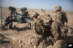 FILE - In this photo provided by Operation Resolute Support, U.S. soldiers with Task Force Iron maneuver an M-777 howitzer so it can be towed into position at Bost Airfield, Afghanistan, June 10, 2017.
