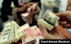 Seorang pegawai valas menghitung uang kertas dollar AS dan rupiah, di Makassar, Sulawesi Selatan, 31 Januari 2013. (Foto: Yusuf Ahmad/Reuters)