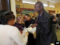 Poll worker Phillip George helps a voter check in at a weekend early voting polling place at the North Hollywood branch library in Los Angeles, Oct. 30, 2016