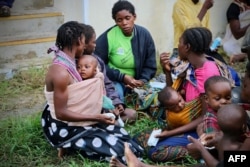 Displaced people get food and drink after arriving at the airport of the coastal city of Beira in central Mozambique on March 19, 2019, which was hit by Cyclone Idai.