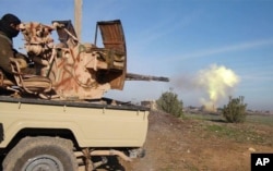 In this image posted on a militant social media account by the Al-Baraka division of the Islamic State group Feb. 24, 2015, a fighter fires a heavy weapon mounted on the back of a pickup truck during fighting in Tal Tamr, Syria.