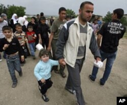Syrian families carry their belongings as they arrive by foot in Wadi Khaled area, northern Lebanon, near the Lebanese-Syrian border, April 28, 2011.