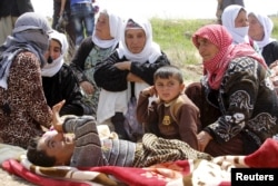 More than 200 Yazidi sect members, freed eight months after they were taken captive by Islamic State militants, wait on the edge of Kirkuk for relocation, April 8, 2015.