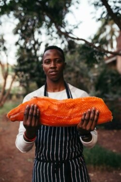 Malachi Mwanki holding his artisanal smoked salmon in Nairobi.