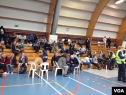 Stranded passengers wait in an arena near Brussels airport after the explosions, March 22, 2016. (N. deVries/VOA)