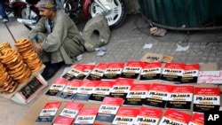 An Egyptian pritzel vender sits next to copies of the new constitution sold on a street in Cairo, Egypt, Saturday, Dec. 28, 2013.