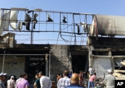 FILE - People inspect buildings damaged by an Iraqi government airstrike in the northern city of Mosul, Iraq, June 28, 2014.