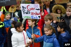 FILE - Youths demonstrate with a banner reading "the greed for profit destroys our earth!" during the "Fridays For Future" movement on a global day of student protests aiming to spark world leaders into action on climate change, March 15, 2019 in Berlin.