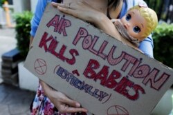 Seorang aktivis lingkungan membawa boneka dan memegang plakat di luar Pengadilan Jakarta Pusat, Jakarta, 16 September 2021.
