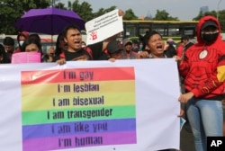 FILE - LGBT activists shout slogans during a rally against a planned revision to Indonesia's criminal code that would criminalize unmarried and gay sex, Feb. 12, 2018, outside the Parliament in Jakarta, Indonesia.
