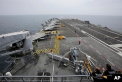 FILE - French sailors work on the flight deck of the French Navy aircraft carrier Charles de Gaulle in the Persian Gulf, March 17, 2015.