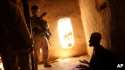 FILE - U.S. Army soldier and an Afghan translator interrogate person in the Bagh village of Khakeran Valley, Zabul province, Afghanistan, June 2005.