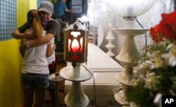 Saldy Delos Santos, father of Kian Loyd, a 17-year-old Grade 11 student, who was killed allegedly in a shootout with police, comforts his son's girlfriend at his wake in their house, Aug. 18, 2017 in Caloocan city north of Manila, Philippines.