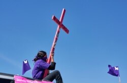 A mother seen atop a vehicle holding a cross with a sign reading "Not one more" during a caravan demanding an end to violence against women and femicide, ahead of a Women's Day protest, in Ciudad Juarez, Mexico March 7 , 2021.