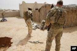 FILE - Chadian troops participate along with Nigerian special forces watched by a U.S. special forces soldier, at right, in a hostage rescue exercise in Mao, Chad, March 7, 2015.