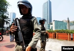 Polisi anti-teror memegang senjata, berjaga-jaga di sebuah distrik bisnis di Jakarta.