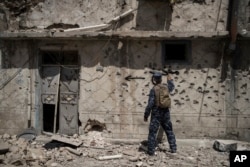 Iraqi policeman spray paint a house exterior to warn that it is booby trapped during fighting against Islamic State militants in the Old City of Mosul, Iraq, June 26, 2017.