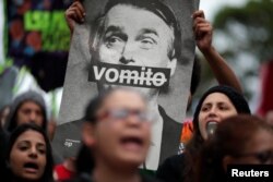 A demonstrator shows a picture of Brazilian presidential candidate Jair Bolsonaro, that reads: "Vomit" during a protest against him at Paulista Avenue in Sao Paulo, Oct. 6, 2018.