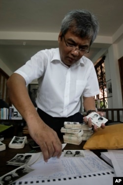 FILE - Director of Documentation Center of Cambodia, Youk Chhang selects photos among about a thousand of newly-discovered photo collection of detainees at the former Khmer Rouge main prison S-21, in his office in Phnom Penh, Cambodia, Monday, Aug. 20, 2012. Photos of near 60 victims detained in the infamous S-21 prison in Khmer Rouge era were unveiled on Monday by Chhang.