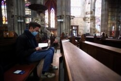Mahasiswa Universitas Wina yang memakai masker wajah belajar di dalam gereja Votivkirche di tengah wabah Covid-19, di Wina, Austria, 6 Oktober 2020. (Foto: REUTERS/Lisi Niesner)