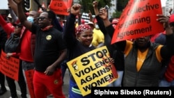 "STOP à la violence contre les femmes", lit-on sur une pancarte lors de la grève générale d'un jour lancée par les centrales syndicales sud-africaines devant le Parlement à Johannesburg, en Afrique du Sud, le 7 octobre 2020.