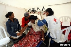 A member of the Colombian Red Cross takes care of a woman who fainted while queueing to stamp her passport, at an emergencies attention center in Cucuta, Feb. 13, 2018.