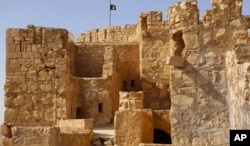 In this picture released May 22, 2015, by the website of Islamic State militants, shows the Islamic State group's flag, top center, raised on the to top of Palmyra castle, in the Syrian town of Palmyra.