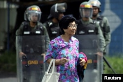 A woman walks in front of Venezuelan National Guards as they stand guard in San Cristobal, May 18, 2017.