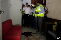 FILE - Bangladeshi security officers inspect the blood-stained site where publisher Ahmed Rahim Tutul and two writers were shot and stabbed by assailants in the office of the Shudhdhoswar publishing house, in Dhaka, Bangladesh, Oct. 31, 2015.
