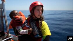 FILE - A worker of the Spanish NGO Proactiva Open Arms holds a boy rescued in the Mediterranean Sea, June 15, 2017.