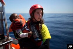 FILE - A worker of the Spanish NGO Proactiva Open Arms holds a boy rescued in the Mediterranean Sea, June 15, 2017.