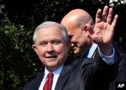 Attorney General Jeff Sessions waves as he leaves South Lawn following a ceremony to honor the 2017 NCAA football national champions, the Alabama Crimson Tide on the White House's South Lawn, in Washington, April 10, 2018.