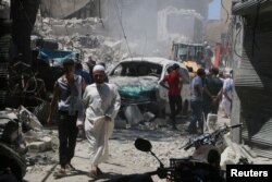 FILE - People inspect the damage at a site hit by a barrel bomb in the rebel-held area of Old Aleppo, Syria, July 11, 2016.