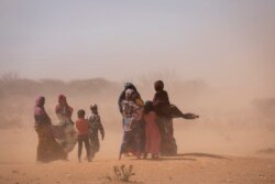 Women and children walk amidst strong dusty winds near Sagalo village in the Korahe zone of the Somali region of Ethiopia, Jan. 21, 2022.