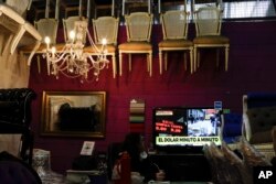 A woman watches news regarding U.S. dollar rates in Buenos Aires, Argentina, Aug. 30, 2018. Argentina's Central Bank on Thursday increased its benchmark interest rate to 60 percent — the world's highest — in an effort to halt a sharp slide in the value of the peso.