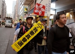 Pro-democracy protesters carry a sign reading "I want genuine universal suffrage" and a Hong Kong national flag during a demonstration in Hong Kong, March 25, 2017.