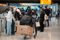 Travelers queue up at the United American Airlines check-in kiosks in the terminal of Denver International Airport, Dec. 26, 2021, in Denver.