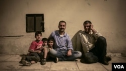 Two men and children wait outside the hotel hoping to be allowed entry. However, City Plaza's popularity means it is now full. (J. Owens/VOA)