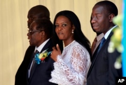 Zimbabwean First Lady Grace Mugabe, center, walks with Zimbabwean President Robert Mugabe at a ceremony to rename Harare International airport to Robert Gabriel Mugabe International Airport in Harare, Thursday, Nov. 9, 2017.