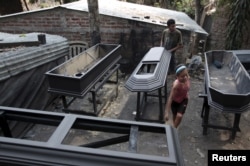 A worker applies sealant to a coffin at El Nuevo Renacer factory in Jucuapa, El Salvador, April 7, 2016.