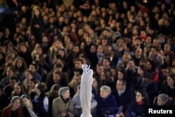 People gather near a statue of the Virgin Mary at the Place Saint-Michel the day after Notre-Dame Cathedral suffered heavy damage from a massive fire that devastated large parts of the gothic structure in Paris, France, April 16, 2019.