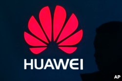 A man is silhouetted as he walks by a Huawei retail store at a shopping mall in Beijing, China, Dec. 11, 2018.